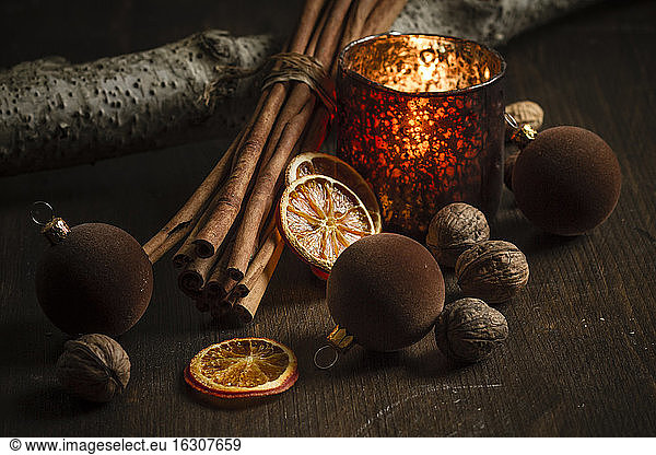 Christmas decoration with tea light candle  christmas tree balls  cinnamon sticks  slices of dried oranges and walnuts on wooden table  studio shot