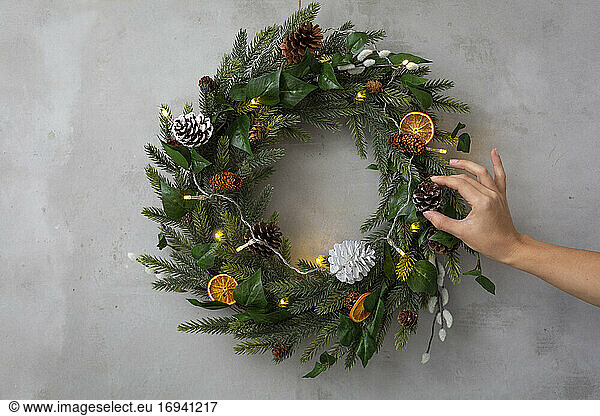 Christmas decorations, close up of person decorating Christmas wreath with ornaments.