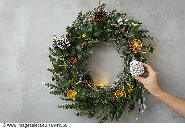 Christmas decorations,  close up of person decorating Christmas wreath with ornaments.
