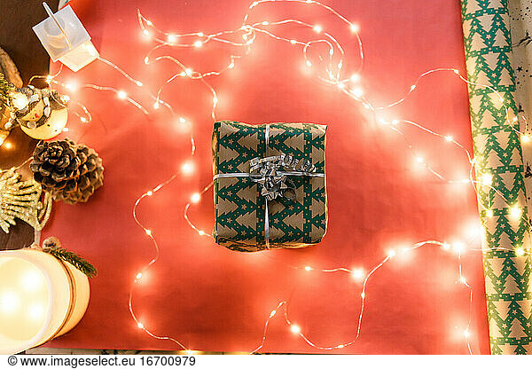 Christmas gift in a wrapper in the middle of decor and gift paper