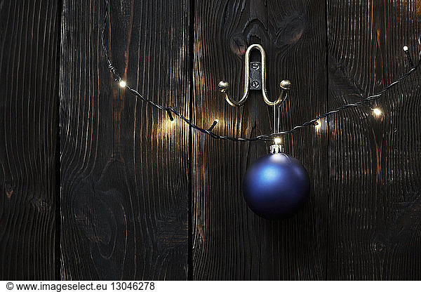 Christmas lights and bauble hanging on wooden wall