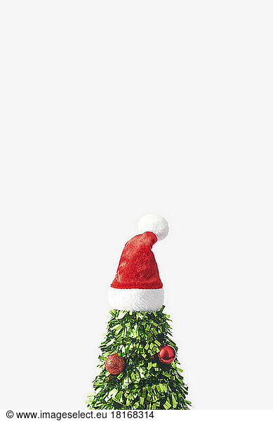 Christmas tree made of green confetti with santa hat on top against white background
