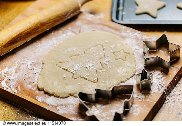 Christmas tree shape pressed into cookie dough beside cookie cutter  close-up