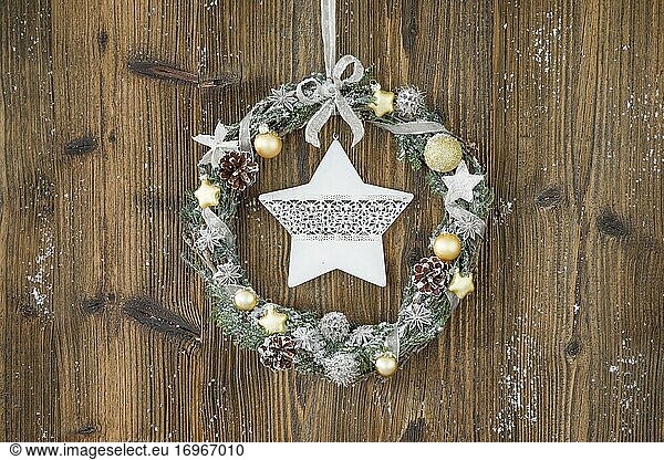 Christmas wreath on brown wooden wall with star
