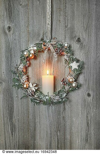 Christmas wreath on wooden wall with candle