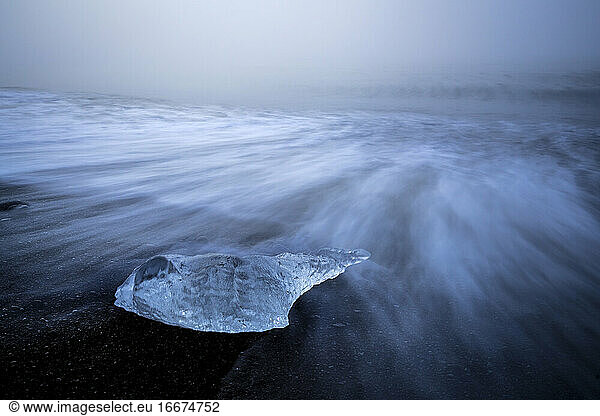 Chunk of ice on sea shore at Diamond beach near Jokulsarlon Glacier Lagoon in foggy weather  Iceland