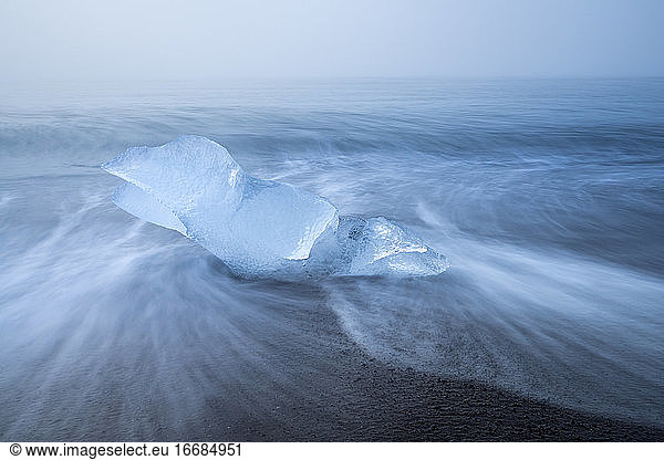 Chunk of ice on sea shore at Diamond beach near Jokulsarlon Glacier Lagoon in foggy weather  Iceland