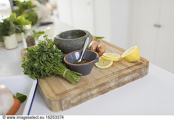 Cilantro and lemons on cutting board with mortar