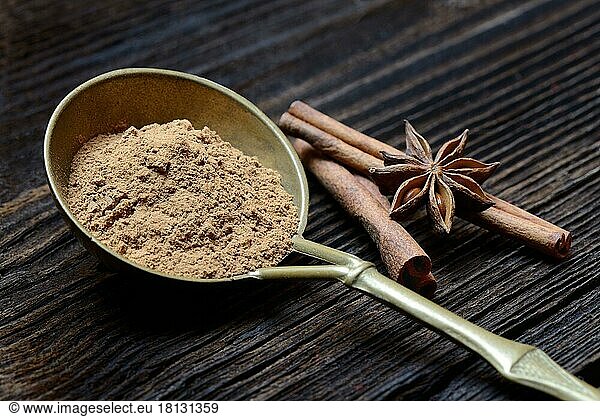 Cinnamonpowder ( Cinnamomum spec.) in brass ladle and star anise sticks