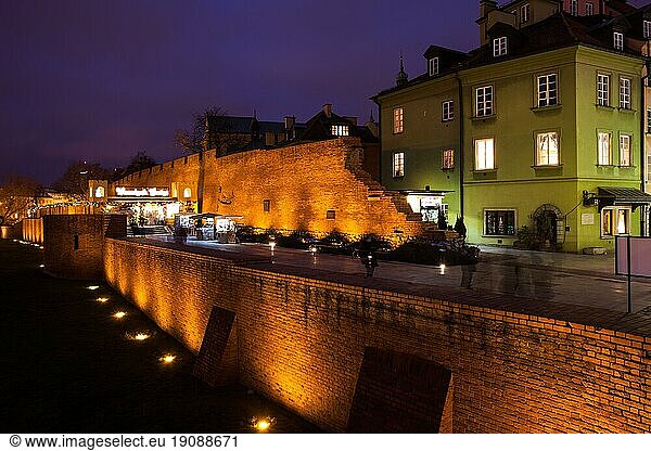 City wall illuminated at night and historic tenement houses in Old Town of Warsaw in Poland