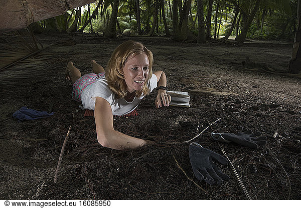 Clare Keating Daly from the Arros research center of the 'Save our seas' foundation with a young Wedge-tailed Shearwater (Puffinus pacificus) in its burrow. Seychelles