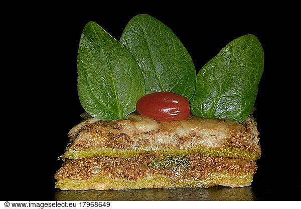 Classic lasagne with spinach leaves and tomato  studio photography with black background