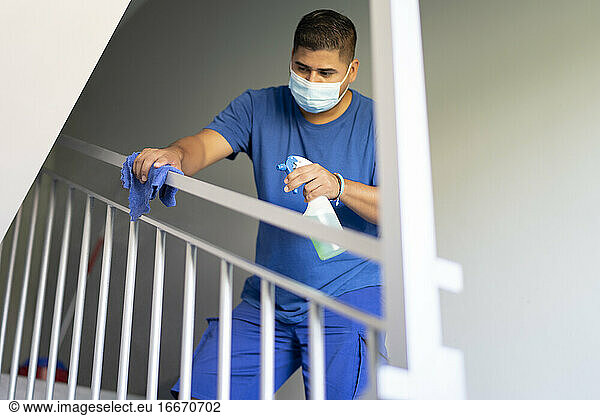 cleaning staff disinfecting the stair railing to avoid covid19