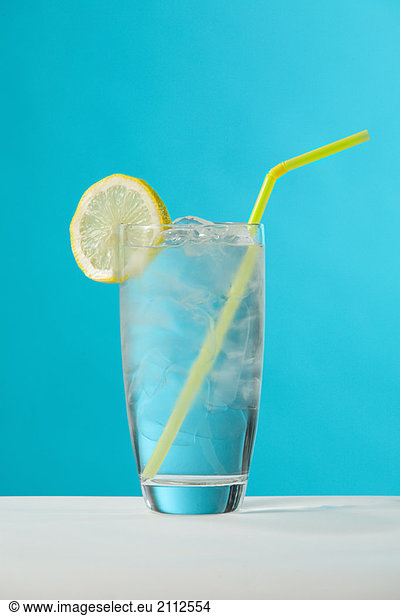 Clear glass of water with lemon and drinking straw