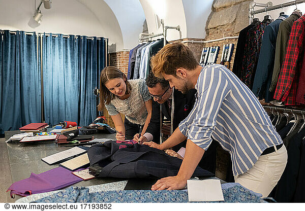 Client discussing sketch with dressmaker and assistant