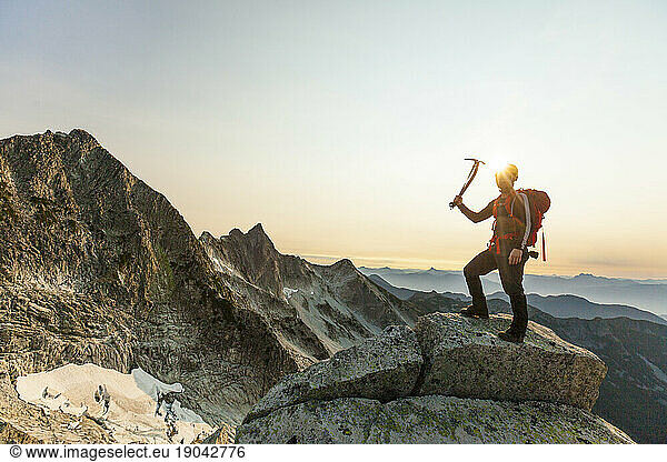 Climber holds ice axe  standing on a rocky mountain ridge
