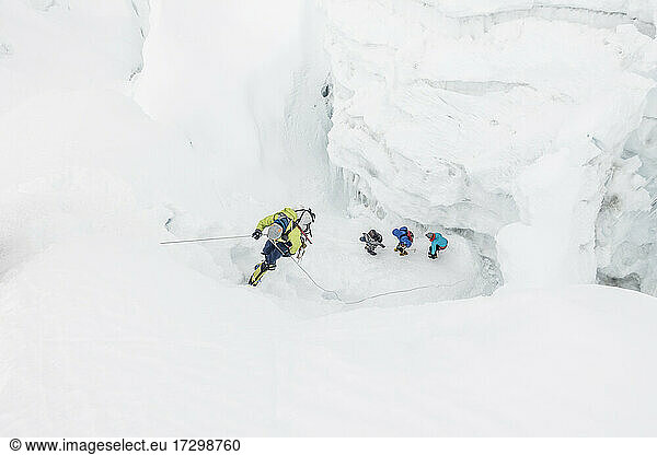 Climber on rappel while team navigates icefall