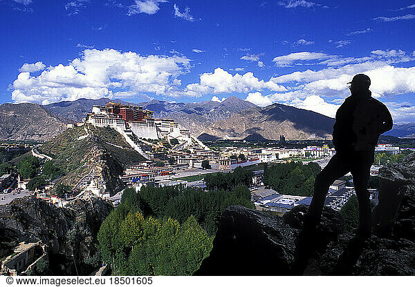 Climber Overlooking Potala Palace in Lhasa Tibet showing the remote mountains