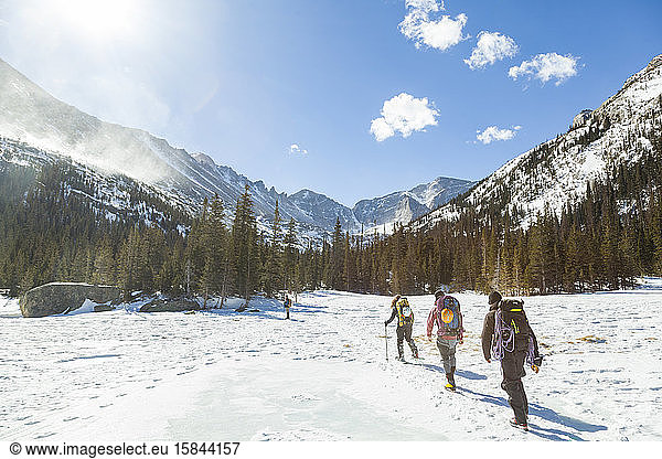 Climbers hike across frozen Mills Lake  Rocky Mountain National Park
