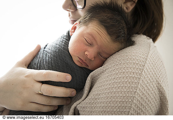 Close In View of Hipster Millennial Mom Snuggling Newborn Baby