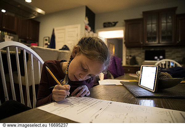 Close-in View of Young Girl At Kitchen Table Doing School Work