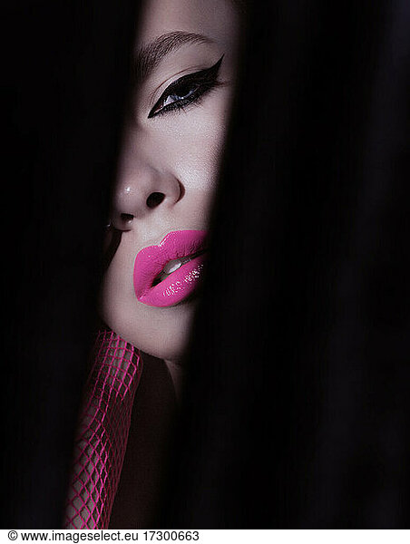 Close-up beauty shot of young pretty model with bright cat-eye make-up. Black Eyeliner. Pink lips. Gorgeous beauty portait