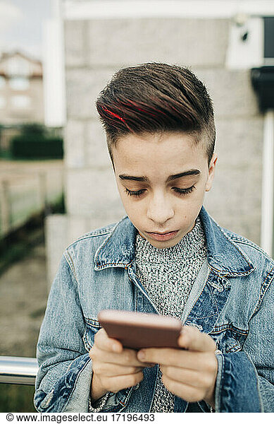 Close up boy teen with red highlights stylish hair using cell phone