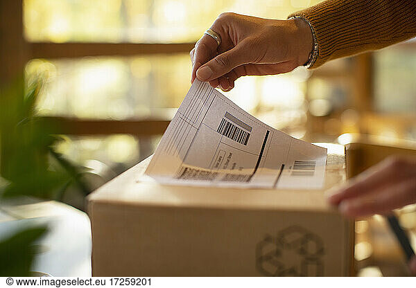 Close up business owner placing shipping label on package