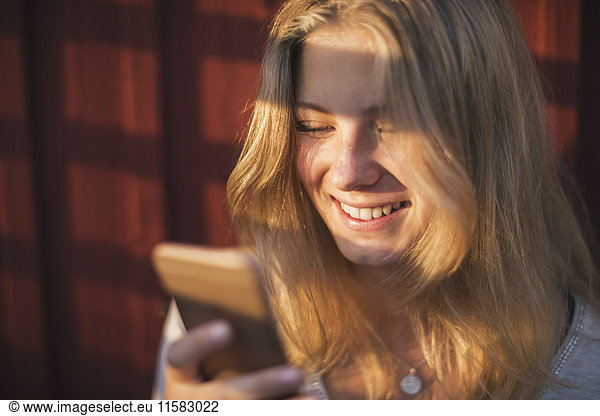 Close-up cheerful teenage girl using mobile phone