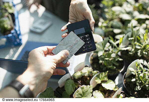 Close up customer paying for plants with smart card