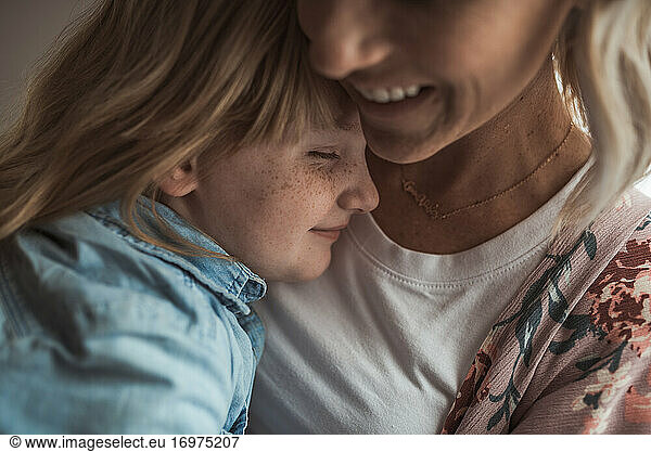 Close up detail of freckled girl being embraced by beautiful mother