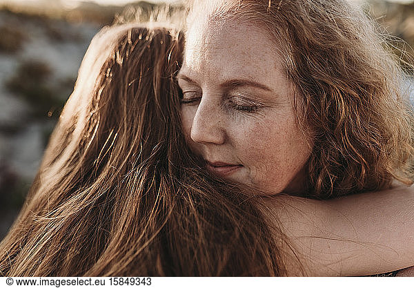 Close up detail of mother's face while hugging daughter at beach