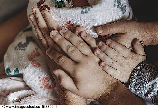 Close up detail of whole family's hands holding newborn son in hospita