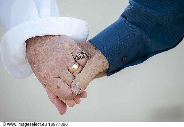 Close-up detail shot of older couple's hands holding each other
