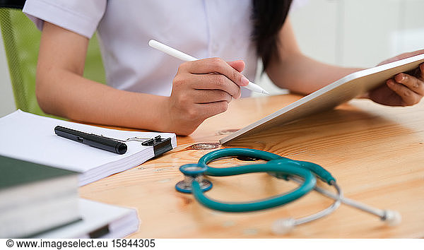 Close up doctor examining medical report while using computer ta
