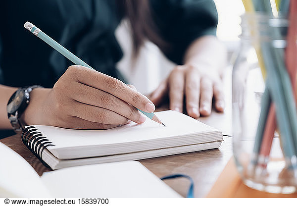 Close up female hands with pen writing on notebook.