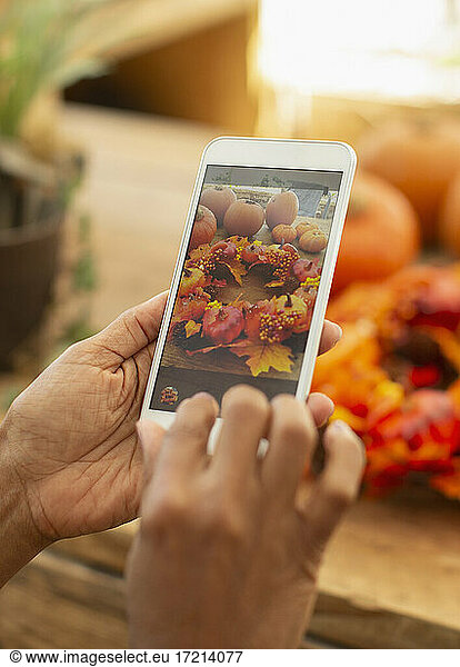 Close up florist with smart phone photographing autumn arrangement