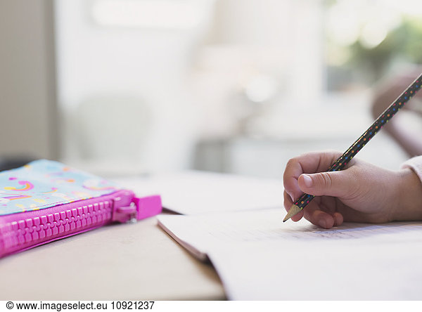 Close up girl doing homework with pencil