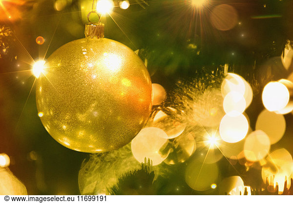 Close up golden ornament and string lights on Christmas tree