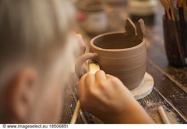 Close up hands of a girl in the process of sculpting a mug with
