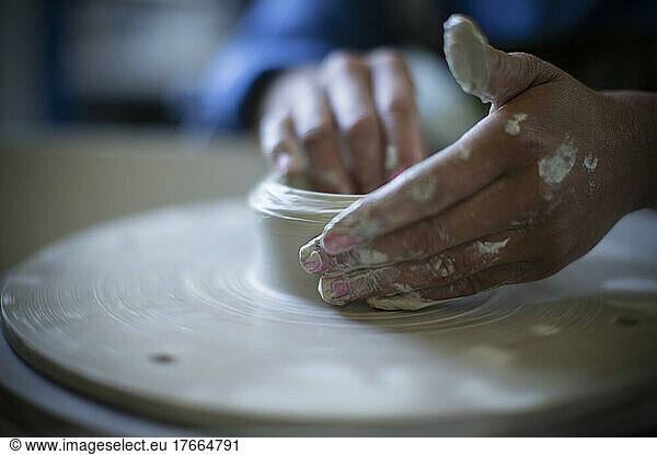 Close up hands of woman using pottery wheel