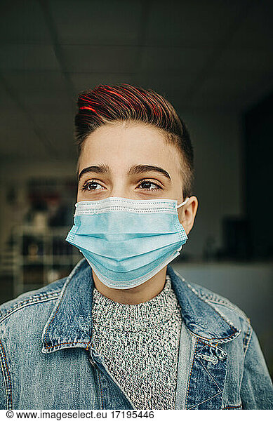 Close up handsome teenager boy wearing mask and denim in hair salon