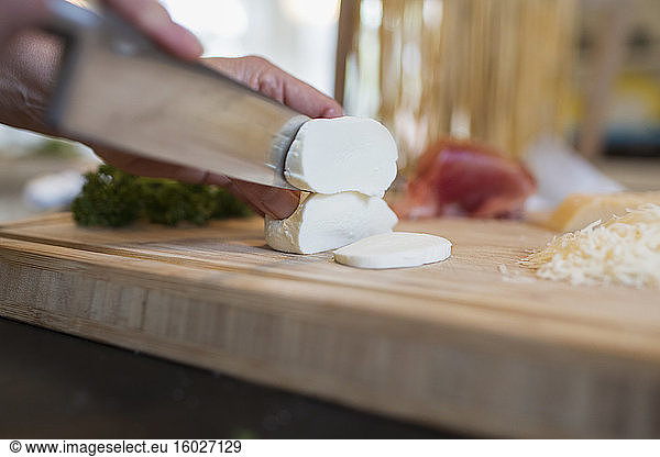 Close up knife cutting into fresh mozzarella cheese