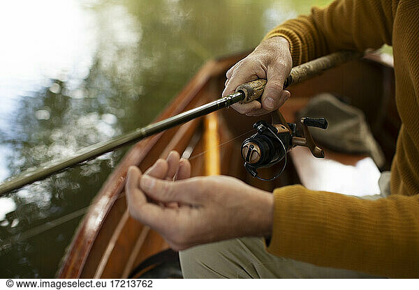 Close up man adjusting fly fishing line in boat