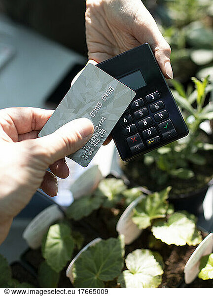 Close up man paying for plants with smart card