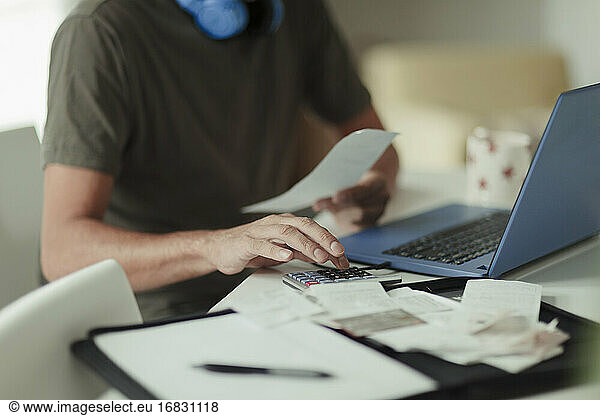 Close up man with receipts and calculator paying bills at laptop