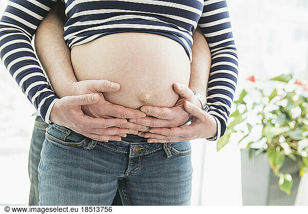 Close-up midsection of husband holding his pregnant wife's belly