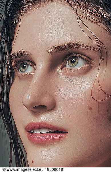Close up model with hydrated facial skin and natural makeup on green