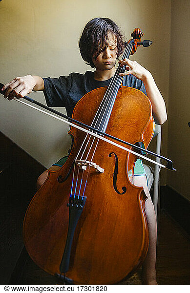 Close-up of a boy with intense focus playing cello in a stairwell