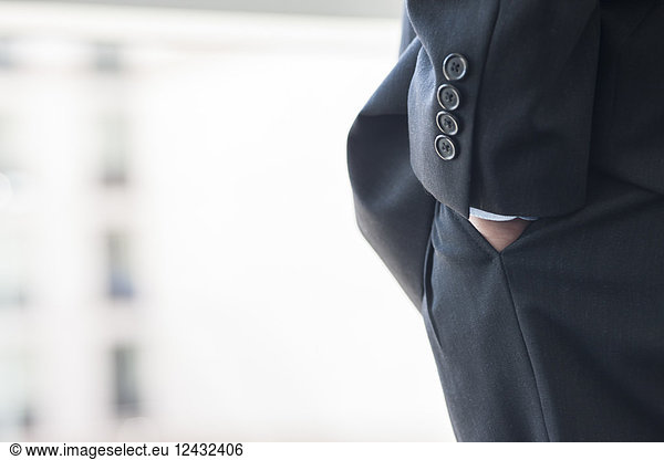 Close-up of a businessman's hand in a suit pants pocket.